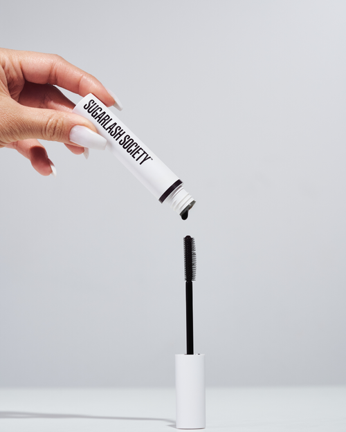 Model holding a tube of black lash and brow Glaze for lash extensions