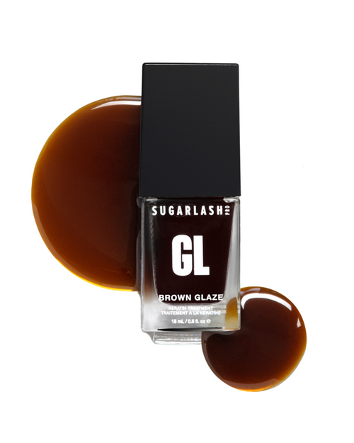 A bottle of Brown Glaze with drops of Glaze around it for your eyelash extensions