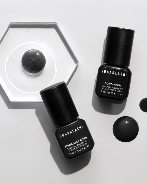 5ml bottle of signature bond noir lash extension glue with drops of lash glue around them.