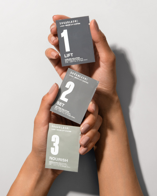 A model holding Lift, Set and Nourish Lash and Brow Lamination sachets.