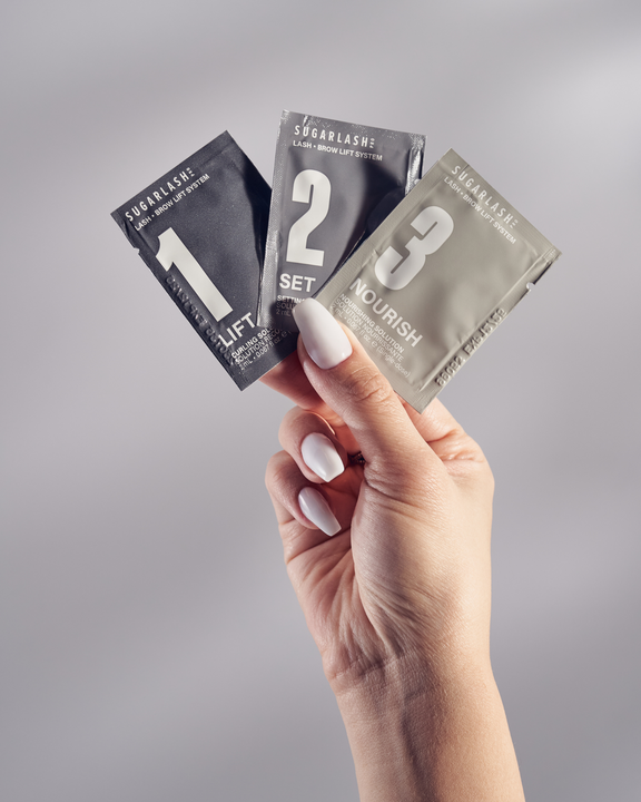Model holding Lift, Set, and Nourish Lash and Eyebrow Lamination sachets.