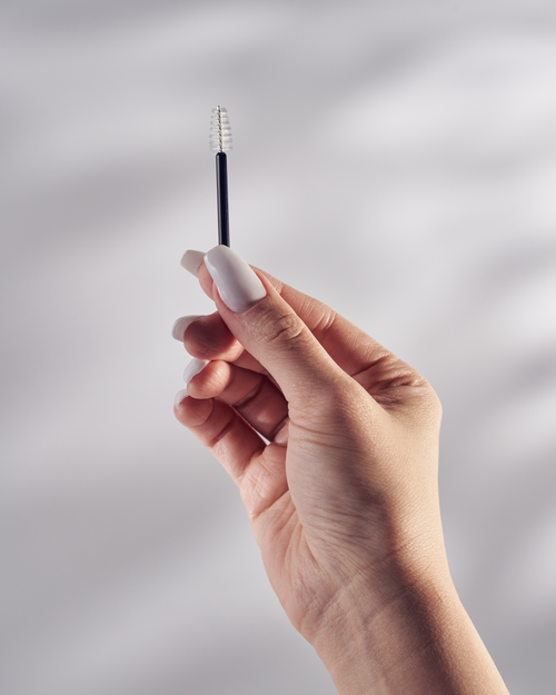 A model holding a Mini Mascara Wand for eyelash extensions.