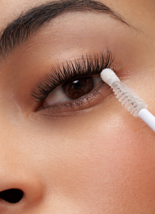 A model's eye with the Cat Eye temporary lash extensions and a lash brush touching her lashes.