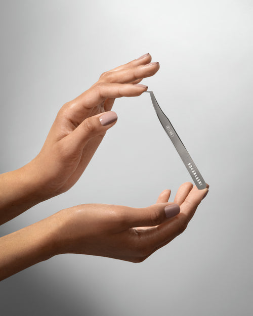 A model holding Volume lash extension Tweezer V-65 between two hands.