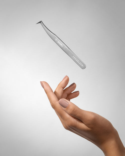 Volume lash extension Tweezer V-Sharp above a models hand.