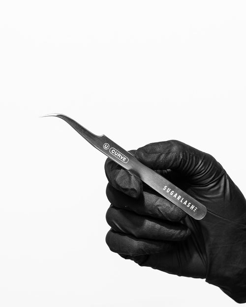 A gloved model's hand holding lash extension Universal Tweezer U-Curve.