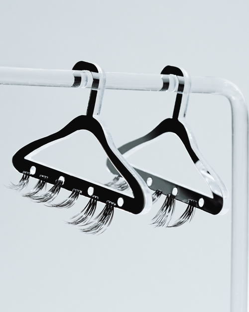 Lash clusters hanging on tiny hangers on a tiny rack.