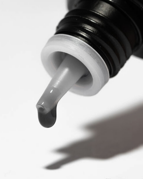 A drop of adhesive coming out of a lash extension bond bottle.