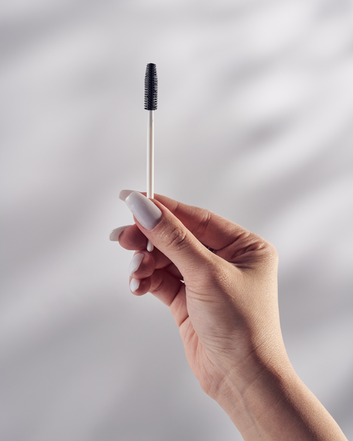 A model holding a Silicone Mascara Wand for eyelash extensions.
